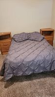Full view of the bed with bedding and two wooden nightstands positioned on either side.