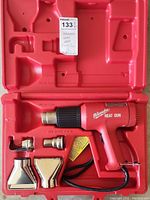 Full view of Milwaukee heat gun, metal nozzles and red plastic carrying case.
