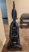 Full view of blue and black Kenmore Progressive beltless upright vacuum cleaner with handle and hose attached.