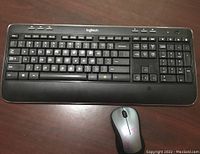 Full view of Logitech wireless keyboard and mouse on a dark wood table.