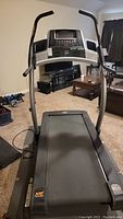 Full view of NordicTrack incline trainer treadmill showing the control console, handlebars, and running belt in a living room setting.