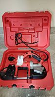 Milwaukee portable band saw inside red carrying case showing the entire tool and case interior