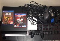 Full lot view showing PS4 console, two games, controller, headsets and cables