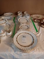 Overview of Aynsley Golden Anniversary pattern dishes including plates and teacups with saucers on table.