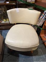 Front view showing the vinyl upholstered seat and curved backrest with nailhead trim.