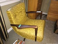 Side angle showing yellow damask upholstery, wooden armrests, and metal legs.