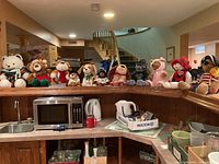 All 11 Chantilly Lane musical plush toys lined up on kitchen counter with microwave and sink below