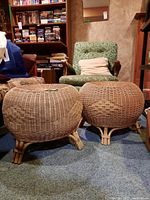 Photo showing two round wicker ottomans placed side by side, highlighting the shape, weave pattern, and partial damage to feet.
