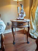 Side table with drawer, placed near sofa and lamp, showing detailing of leg and handle.