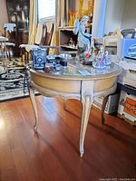 Side view of the round wood table with decorative items on top including figurines and vintage cameras.