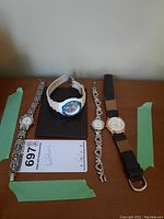 Four wristwatches laid on table, visible different designs and bands