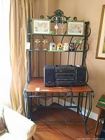 Photo showing the metal wine and baker's rack with wooden top surface and four storage areas, with some decorative items and a stereo on it (contents not included)