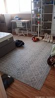 Full view of the beige and gray patterned area rug in a bedroom setting, showing its overall size and design.