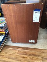 Front striking wooden panel of cajon with Meinl logo and screws visible.