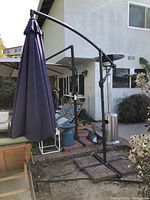 Full view of the navy blue cantilever-style patio umbrella with curved arm and weighted base near a patio seating area.