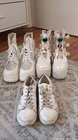 Front view of two pairs of white girls boots and one pair of white sneakers showing wear and tear.