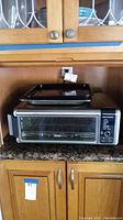 Ninja air fryer toaster oven with two cooking pans on top, closed door, control panel visible.