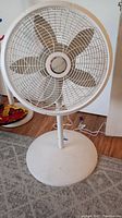 Photo of the white Lasko oscillating floor fan showing five blades and round base on wooden floor