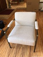 Front view of chair showing beige fabric seat and back with metal armrests and legs