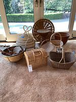 Various woven baskets, woven stool, bamboo bowl and musical instruments inside bowl, shown on carpeted floor by glass doors.