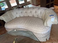 Photo of curved beige Breuners sofa with tufted back and rolled arms, showing front and side view
