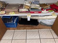 Shelved linens, napkins, card table covers, and Christmas decorations stacked on two shelves, various sizes and colors folded neatly.