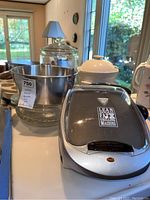 Front view of George Foreman Lean Fat Grilling Machine, mixing bowls, and glass bakeware on a table with natural light from a window.