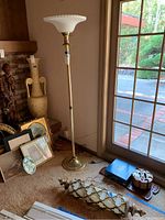 Full view of brass floor lamp standing next to a window and decorative hanging lamp on floor