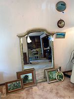 Full view of the large ornate mirror, barometer above, and multiple framed wall art pieces arranged around base of mirror and nearby wall