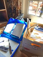 Blue plastic storage boxes opened, showing interior compartments and white papers inside.