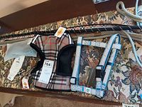 Photo of two dog harnesses, gray rope leash, black patterned leash, and bow ties arranged on a fabric surface