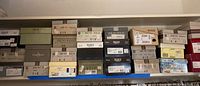 Shelf with multiple shoe boxes, including brands Clarks, Bruno Magli, Ecco, and more, sizes mainly 8 or 8.5.