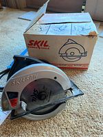 Photo of Skilsaw circular saw with original box showing the saw blade and overall body design.