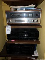 Three units stacked on wooden shelves: receiver at top, cassette deck middle, CD player bottom.