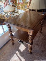 Side angle view of the wooden end table showing detailed turned legs and lower shelf.