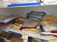 Stacked and folded table cloths and placemats on shelving, showing different textures, colors and patterns