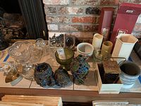 Wide view of assorted glass bowls, candleholders, and decorative items on display including stained glass mosaic candleholders and a patterned white ceramic pitcher.