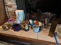 Lot overview showing various decorative and functional items including metal and glass vase, lobster serving dish, oil lamp, ceramic cups, brass kettle, and small glass bottles.