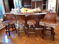 Four vintage bar stools with brown vinyl seats and floral fabric upholstery on the bases arranged in front of kitchen bar.