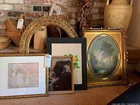 Overview of all framed pieces and empty frame laid against brick background near fireplace