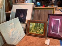 Photo showing several framed art pieces arranged together including the stone relief and paintings.