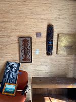Wide view showing multiple wall art pieces including carved wooden sculptures, framed paintings, and a gold abstract canvas.