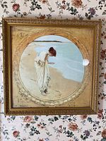 Full view of framed wall art showing a woman in white dress at beach with ornate gold frame