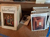 Large-format print set including 'Masterpieces of Italian Painting' and Architectural Digest magazines stacked on floor.
