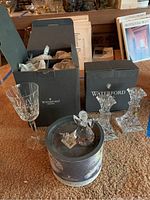 Waterford Crystal box with some glasses, two candlesticks in box, and Swarovski angel in a crystal container, plus Wine Makers year poster in background.