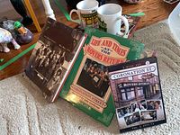 Photo shows two Coronation Street hardcover books, three mugs, and a puzzle box.
