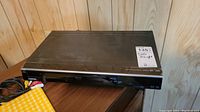 Full top and front view of Toshiba DR430 DVD player with AV cables visible on wooden surface.