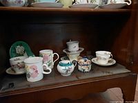 Shelf view showing all pieces together (teacups, saucers, mugs, sugar bowl, teapot)