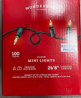Photo of a red Philips Wondershop box showing clear mini incandescent lights on green wire, 100 bulbs, 24'8" lighted length, indoor and outdoor use.