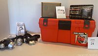 Photo displaying three Brinkman headlamps, Black & Decker orange toolbox with latches, packing tape dispenser with 10 rolls, and the pest repellent device box.